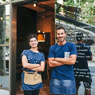 Deux employés souriant à la porte principale du magasin.