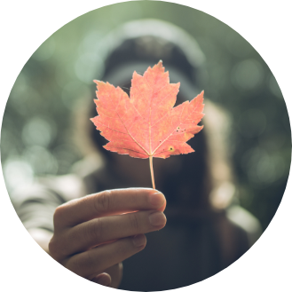 Woman holding a maple leaf in front of her.