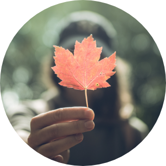 Une femme tenant une feuille d’érable devant elle.