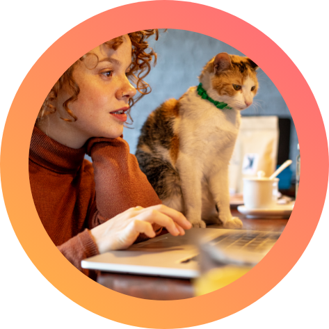Woman working on a laptop accompanied by a cat.